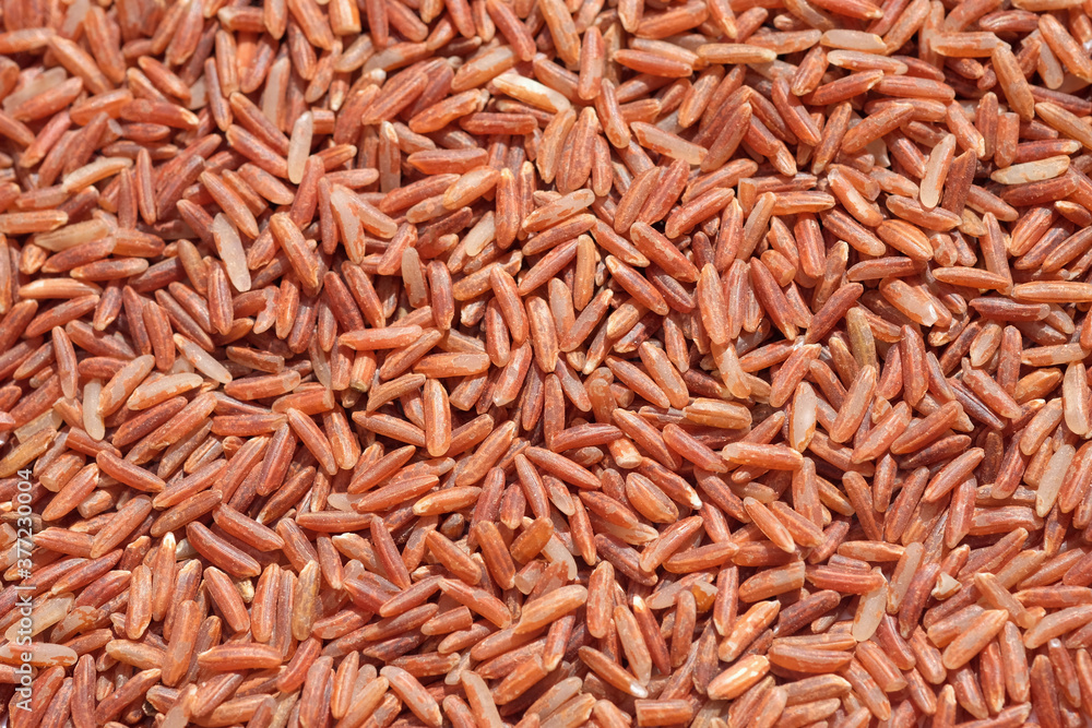 Brown rice uncooked grains background. Dry red rice close up. Brown rice uncooked grains background. Dry red rice close up.