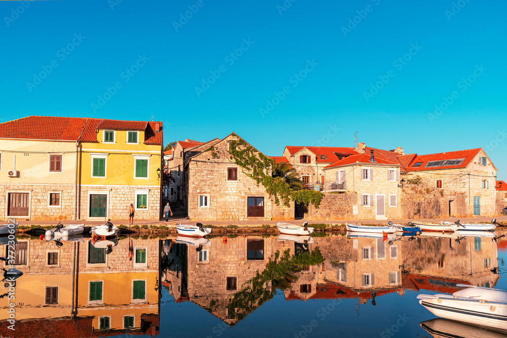 Vrboska village embankment, houses are reflected in the water. Hvar island, Croatia.