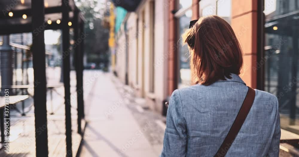 Young Businesswoman Using SmartPhone, Going to Work in the Sunny Morning City. SLOW MOTION, Gimbal Stabilizer. Attractive Professional Business Woman with a cell phone in a city. Lens Flare. Young Businesswoman Using SmartPhone, Going to Work in the Sunny Morning City. SLOW MOTION, Gimbal Stabilizer. Attractive Professional Business Woman with a cell phone in a city. Lens Flare.