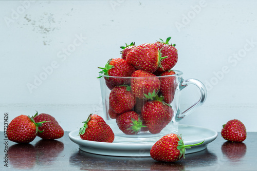 A cup on a plate filled with strawberries