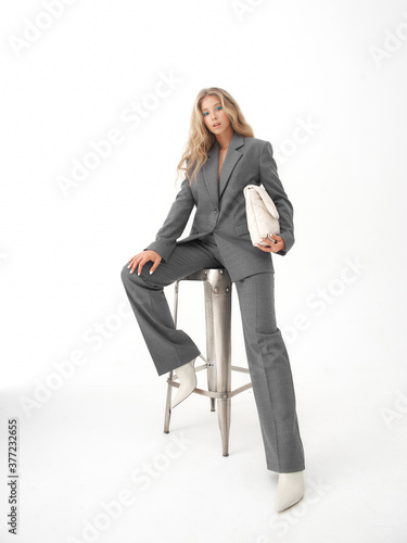 High fashion full length portrait of young beautiful female blonde model in classic gray male suit. 