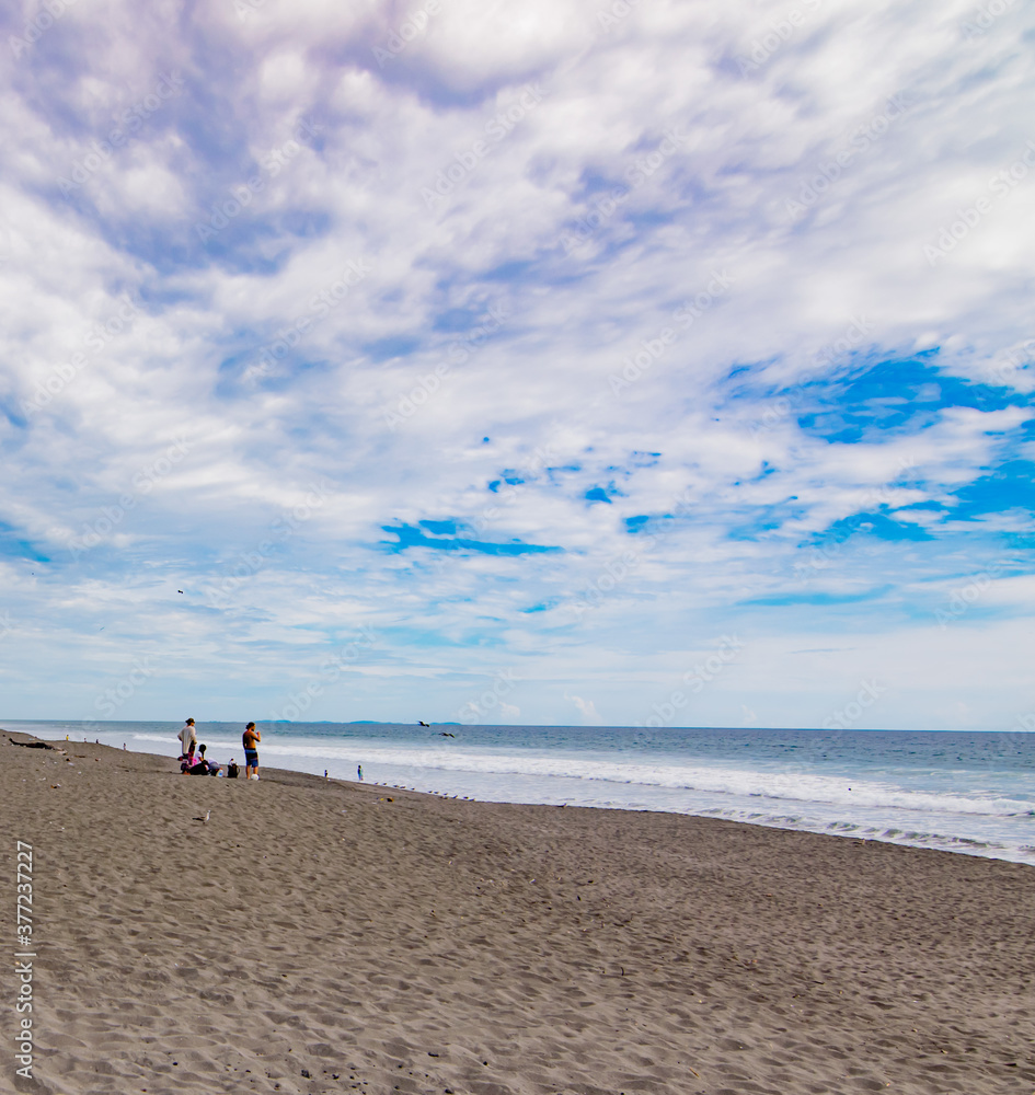 People enjoying La Barqueta beach, during a summer day with a partially cloudy sky. This is a sea turtle nesting site