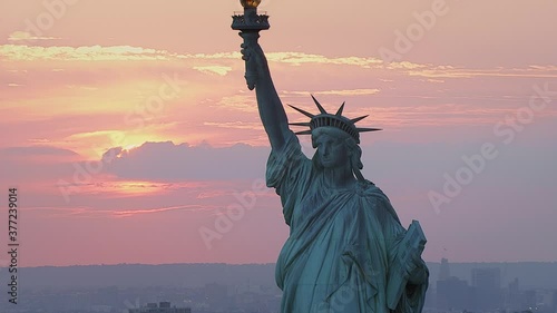 Medium aerial rotating on Statue of Liberty at colorful sunset