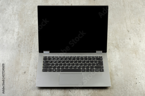 Notebook computer with black empty screen over concrete background