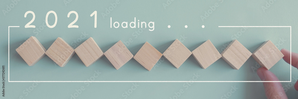 Hand holding wooden blocks in loading bar for 2021 Goal planning business concept Hand holding wooden blocks in loading bar for 2021 Goal planning business concept
