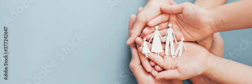 Adult and children hands holding paper family cutout, family home, foster care, homeless charity support concept, family mental health, budgeting during recession concept photo