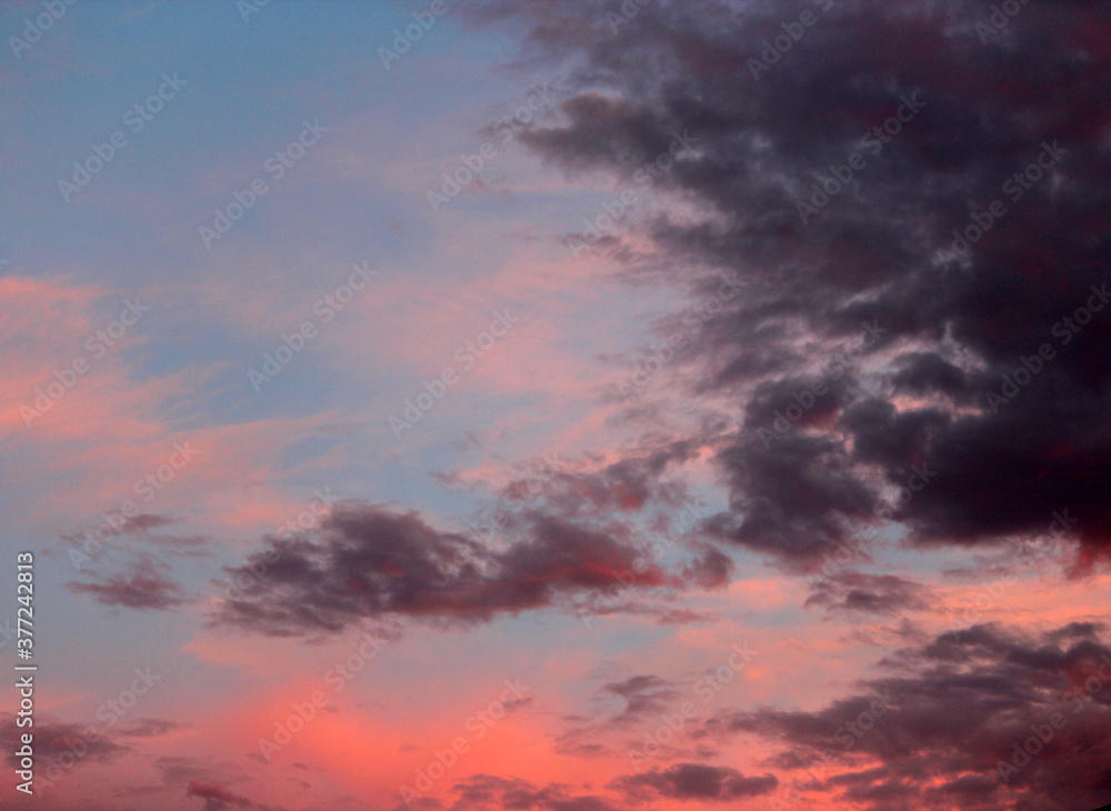 Dainty orange and pale salmon pink clouds  at sunset  in a blue Australian sky in late winter  add color to the skyscape as evening approaches.