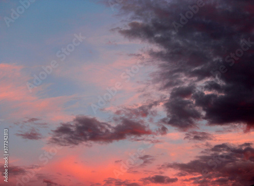 Dainty orange and pale salmon pink clouds at sunset in a blue Australian sky in late winter add color to the skyscape as evening approaches.