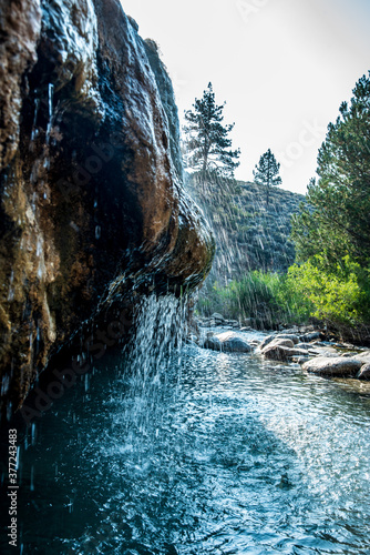natural hot spring waterfall flowing over rock face along mountain stream photo