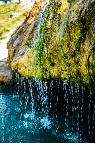 steaming hot water of hot springs waterfall flowing over rock and streaming into pool photo