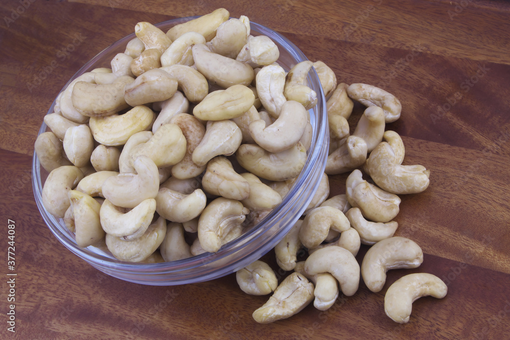 Cashew nuts in glass bowl on wooden table Cashew nuts in glass bowl on wooden table