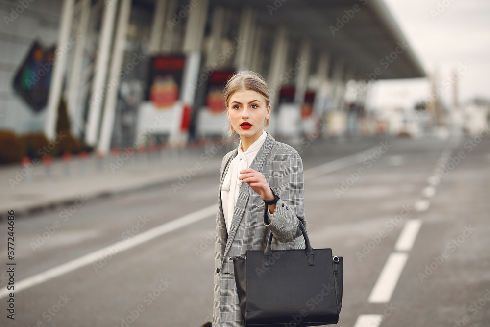 Woman by the airport. Girl with suitcase. Lady in a gray jacket.