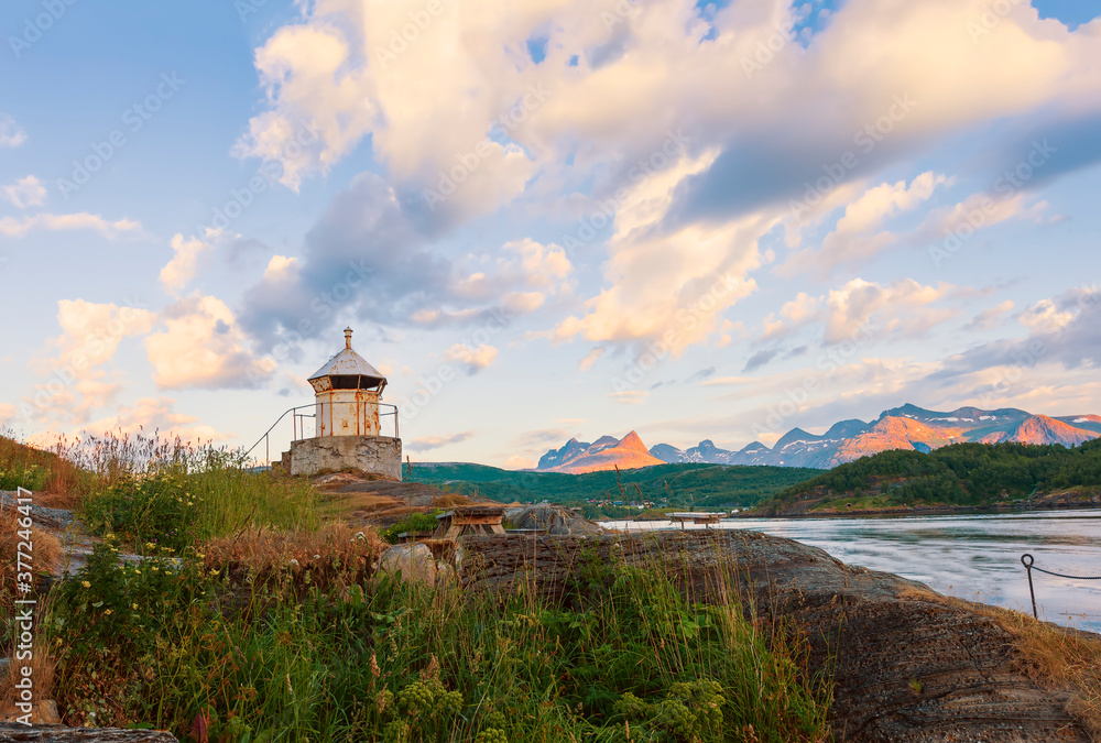 Old lighthouse on the shore of the Saltstraumen straitat sunset.Norway