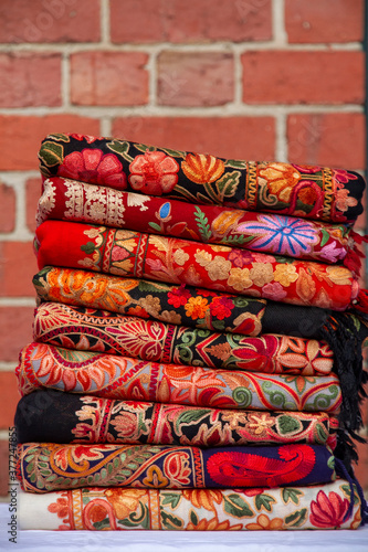 Kashmiri embroidered wool shawls folded in a stack. 