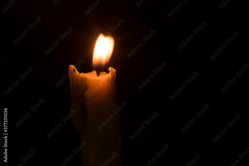 The candle was lit in a black religious background. The candle was lit in a black religious background.