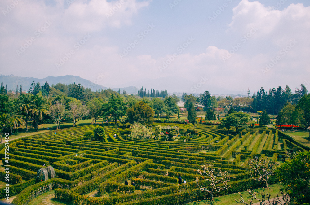 Bogor, Indonesia - A view of the flower themed park Taman Bunga Nusantara in a cloudy afternoon with a top angle view to a labyrinth field with people walking around and inside of it.