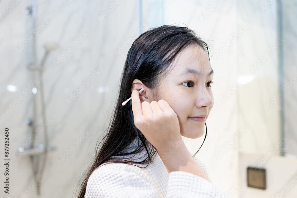 Asian child girl cleaning the external ear canal with a cotton swab
