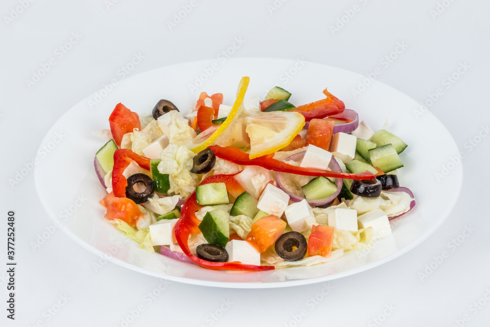 White, round plate with Greek salad on a white background