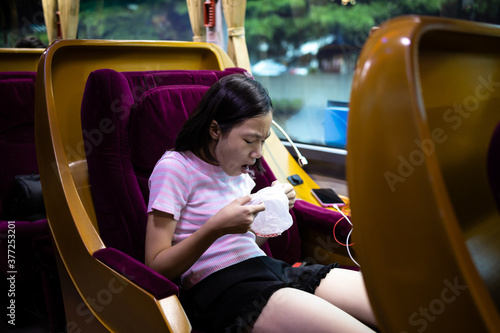 Quadro su tela Unhappy asian child girl about to throw up,puking,motion sickness symptoms, holding sick bag,sad female teenage vomiting in a bus suffers from motion sickness,feels dizziness and nausea from carsick