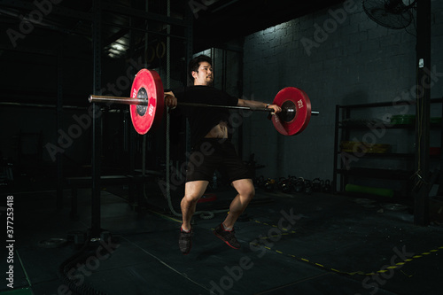 Obraz na plátně Fit muscular sport male bodybuilder workouts snatch lifting with barbells traini