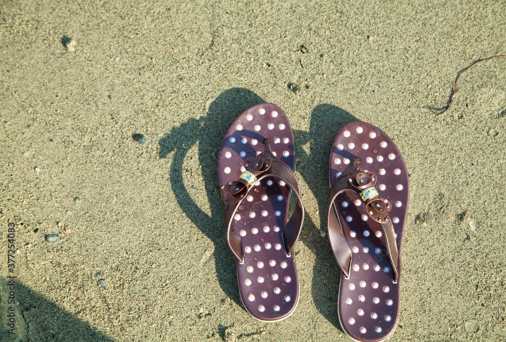 Naklejka premium Brown pair of sandals on the beach.