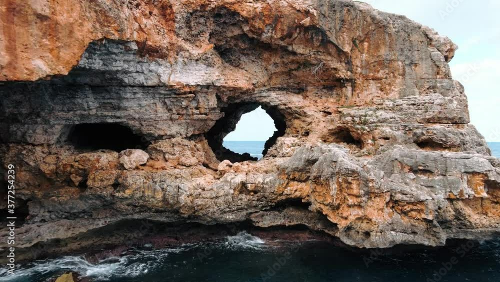 Aerial flying through a cave on a limestone cliff and revealing the ocean on the other side Aerial flying through a cave on a limestone cliff and revealing the ocean on the other side