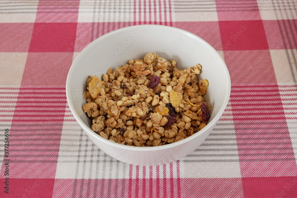 A bowl of whole grain muesli on a table with a red and white tablecloth A bowl of whole grain muesli on a table with a red and white tablecloth