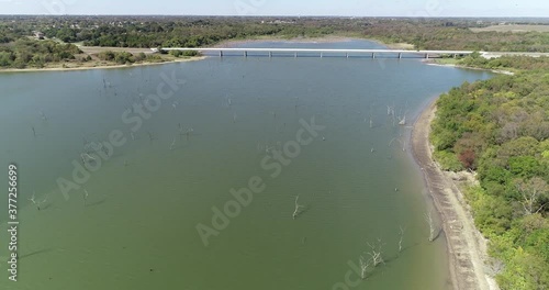 Aerial video of Lake Lavon on the North West side with trees in the water approaching a bridge. photo