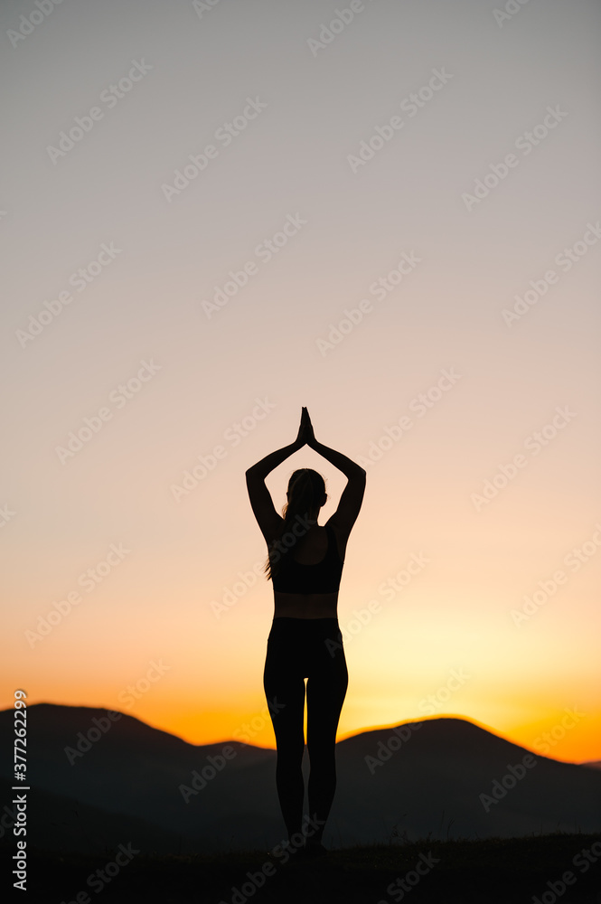 Silhouette woman balanced, practicing meditation, zen energy yoga in mountains. Healthy lifestyle concept. Young girl doing fitness exercise sport outdoors. Morning sunrise. Relax in nature. Back view Silhouette woman balanced, practicing meditation, zen energy yoga in mountains. Healthy lifestyle concept. Young girl doing fitness exercise sport outdoors. Morning sunrise. Relax in nature. Back view