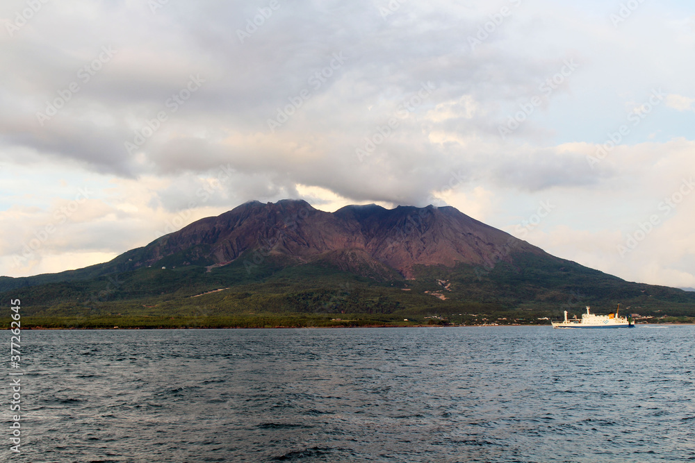 Closeup view of ferry passing by Sakurajima during sunse