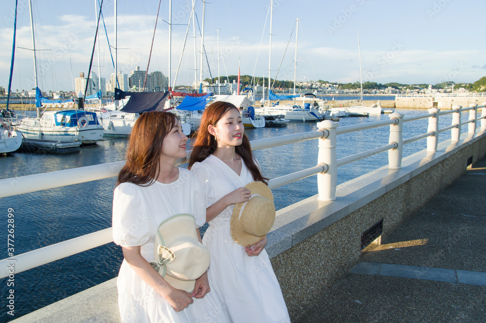 夕暮れのヨットハーバーで休憩する二人の女性