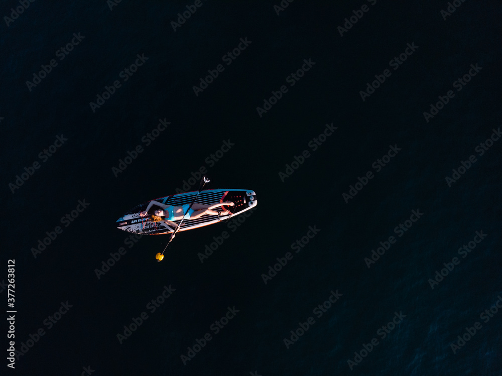 Naklejka premium Attractive Woman on Stand Up Paddle Board, Woman paddling on sup board and enjoying turquoise transparent water. Tropical travel, wanderlust and water activity concept. Sunset and relax