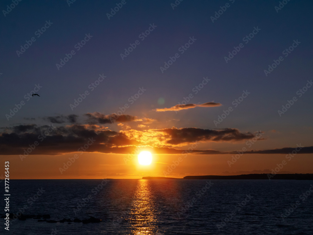 Sunset sky over ocean, Galway bay, Ireland, Warm orange and dark blue tones, Sun flare. Nobody.