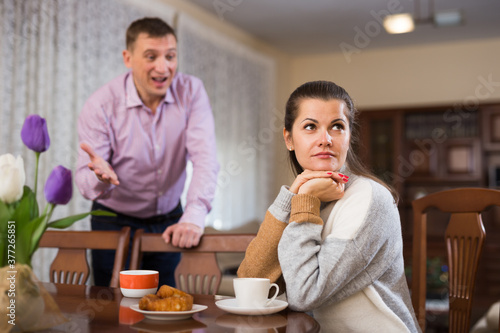 Angry man scolding his offended wife at home