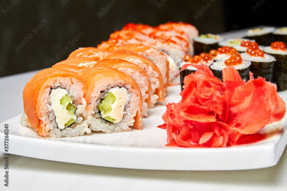 Rolls with salmon and cucumber, cheese and wasabi on a white plate. Closeup, selective focus Rolls with salmon and cucumber, cheese and wasabi on a white plate. Closeup, selective focus