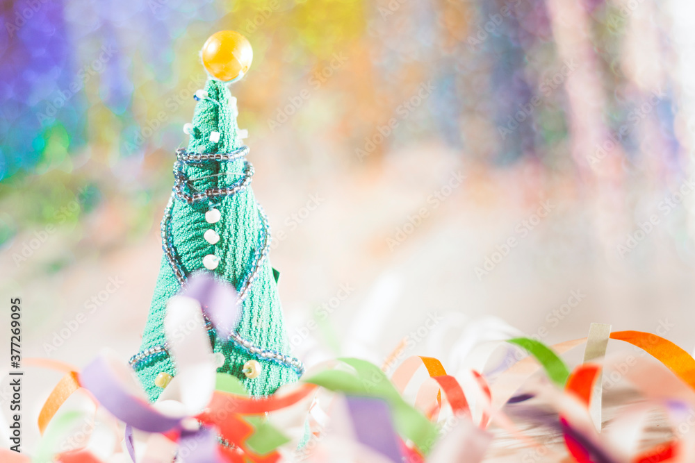 Happy new year and Christmas greeting card. Bokeh in the background, scattered confetti in the foreground and a Christmas tree. Selective focus.