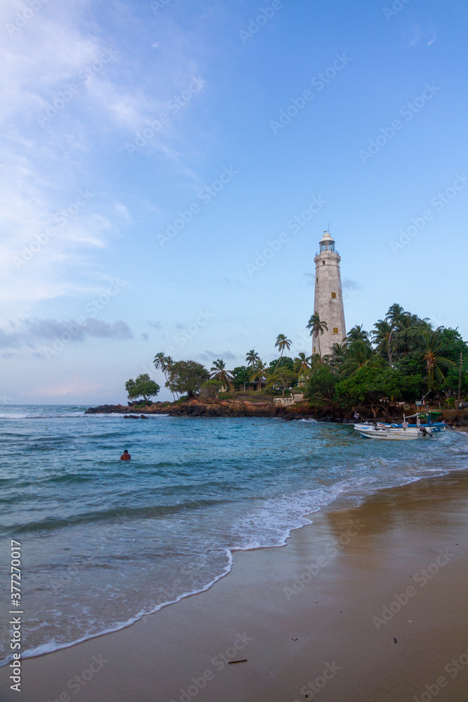 A lighthouse on the south coast of Sri Lanka, flanked by palm trees