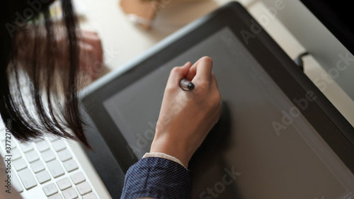 Female designer drawing on graphic tablet in office room