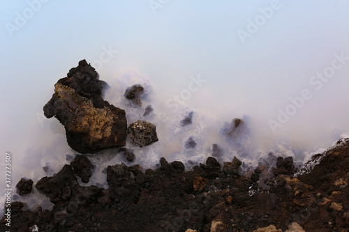 Silicea Sediments in the blue lagoon in iceland, black rocks and light blue and white water, known for skincare, skin treatments and healthy living.