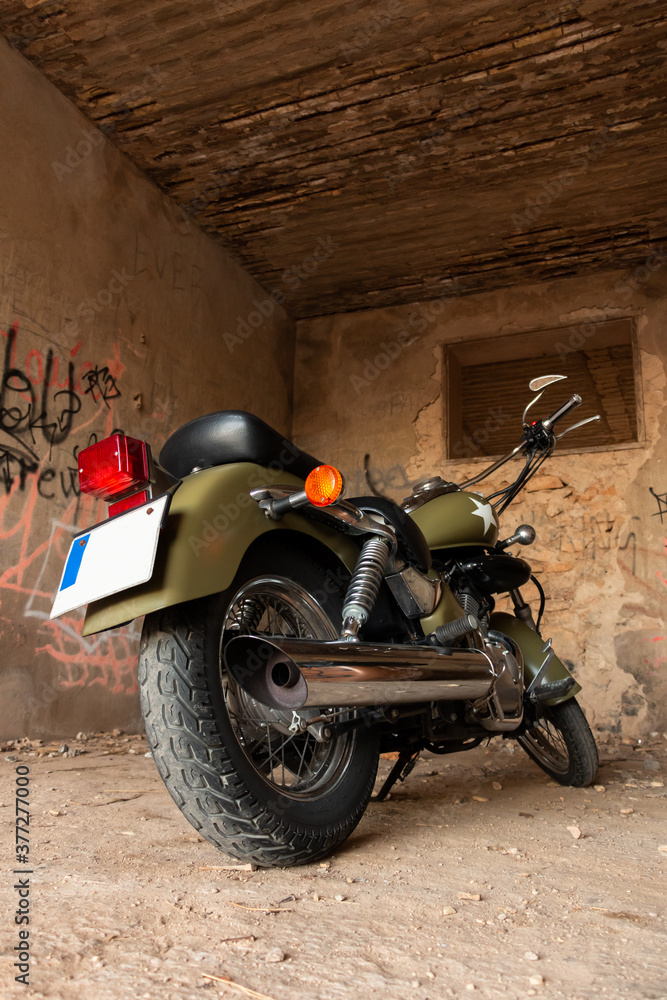 Rear vision of a green vintage custom motorcycle parked in a old shed. Road trip concept