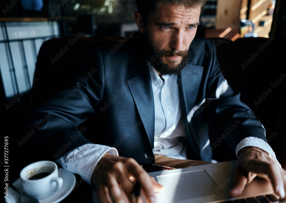 business man in suit in cafe in front of laptop with a cup of drink official business man in suit in cafe in front of laptop with a cup of drink official