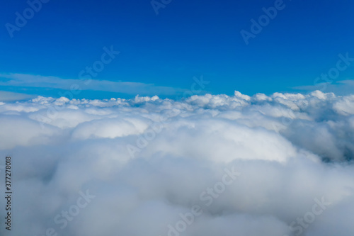 Light clouds seen from airplane. Blue endless sky above fluffy clouds.