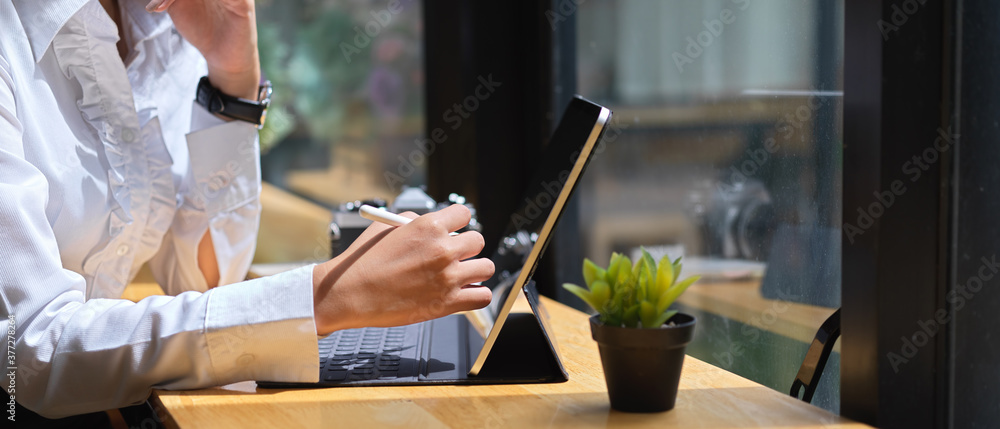 Obraz premium Ręka za pomocą cyfrowego tabletu z rysikiem na drewnianym stole