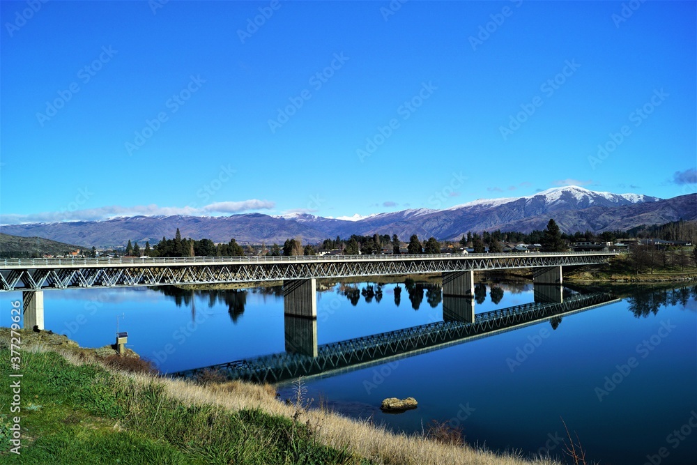 A bridge with blue sky crossing a river on a drive from Queenstown to Christchurch