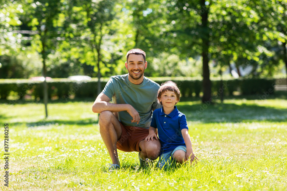 Fototapeta premium family, fatherhood and people concept - happy smiling father with little son at summer park