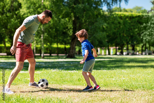 family, fatherhood and people concept - happy father and little son with ball playing soccer at summer park © Syda Productions