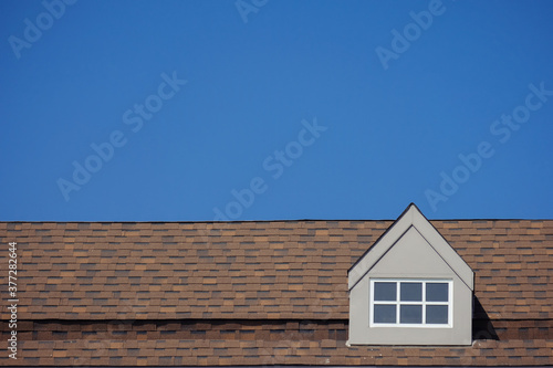 orange roof of the house with white window frame in dark blue clear sky