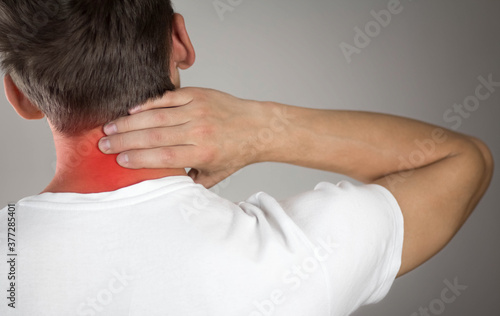 Pain in the neck of a man. Highlighted in red. On a gray background. Close up