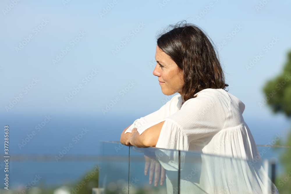 Pensive adult woman  looking away on a balcony