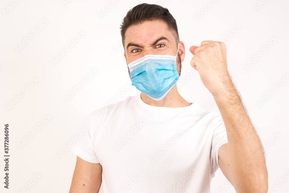 Fierce confident European dark-haired man holding fist in front of him as if is ready for fight or challenge, screaming and having aggressive expression on face. Isolated over gray background. Fierce confident European dark-haired man holding fist in front of him as if is ready for fight or challenge, screaming and having aggressive expression on face. Isolated over gray background.